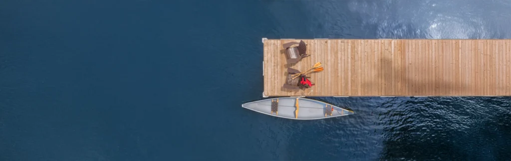 canoe next to dock with chairs on lake